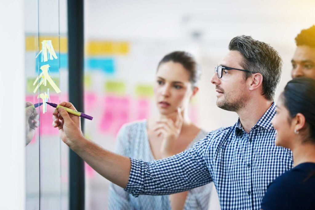 Grupo de trabajo maximizando la recuperación de deudas frente a un cristal lleno de post-its dcl gestión